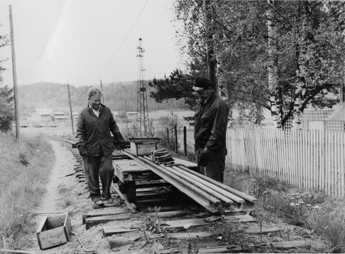Riving av Urskog-Hølandsbanens spor på Bjørkelangen. Arbeidet utføres med håndkraft, og skinnemateriellet kjøres inn med håndtralle. Hans Bådahl t.v.