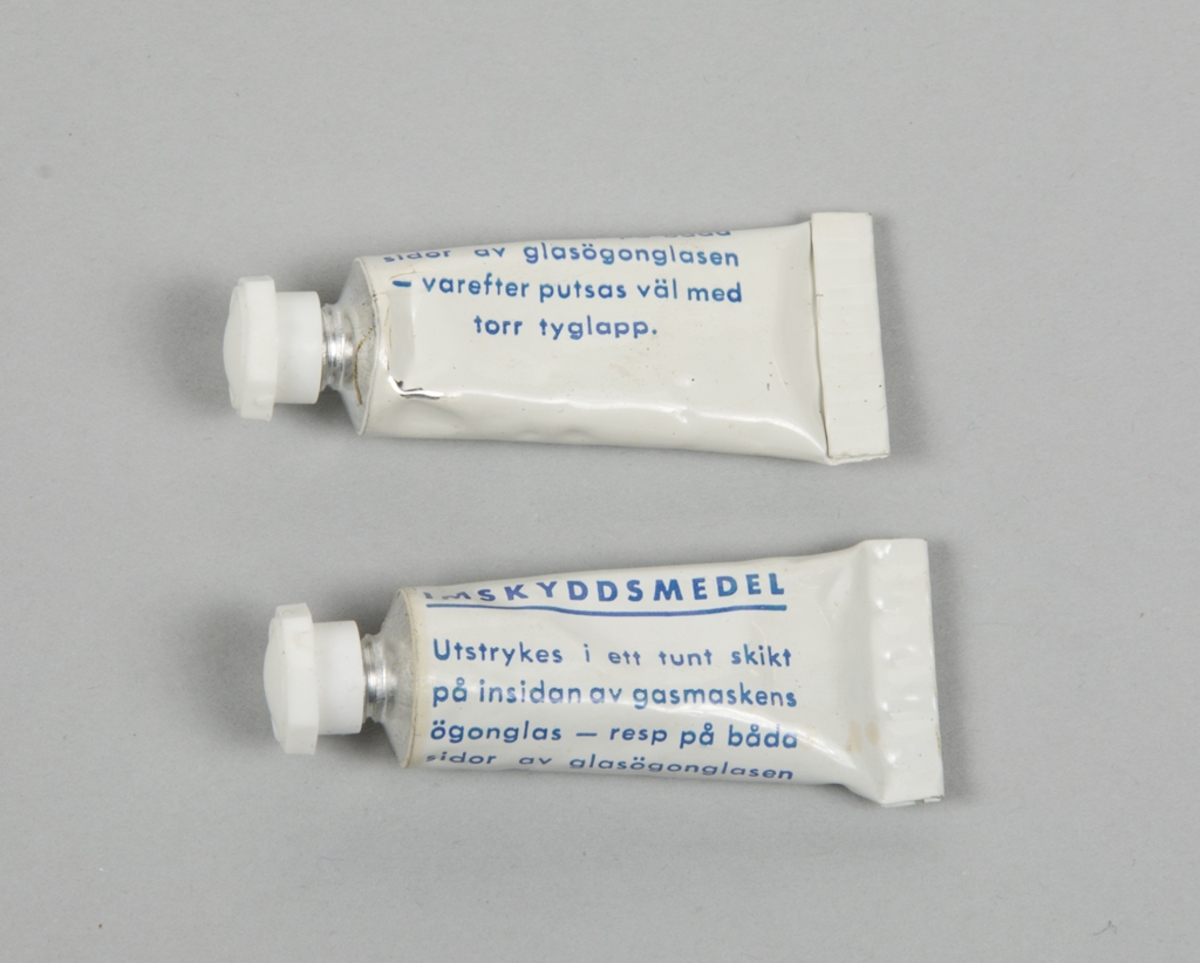 Två stycken skyddsmasker med väska och tillbehör.
Skyddsmask 5 i grönt gummi med blått plastskydd, filterförstärkning på vänster sida.

2 st. skyddsmask 5
2 st. Filter 13
2 st. Väska 06MT
2 st. C-vätskeskydd för kropp
2 st. C-vätskeskydd för fot
2 st. imskyddsmedel
2 st. par Skyddshandske (saknas)