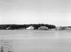 Hägernäs flygstation 1924. Vy från vattnet av tälthangarer, personer och flygplan.