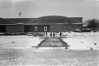 Tre personer i arbete med rälsslip framför hangar på F 2 Roslagens flygflottilj, vintertid 1935.