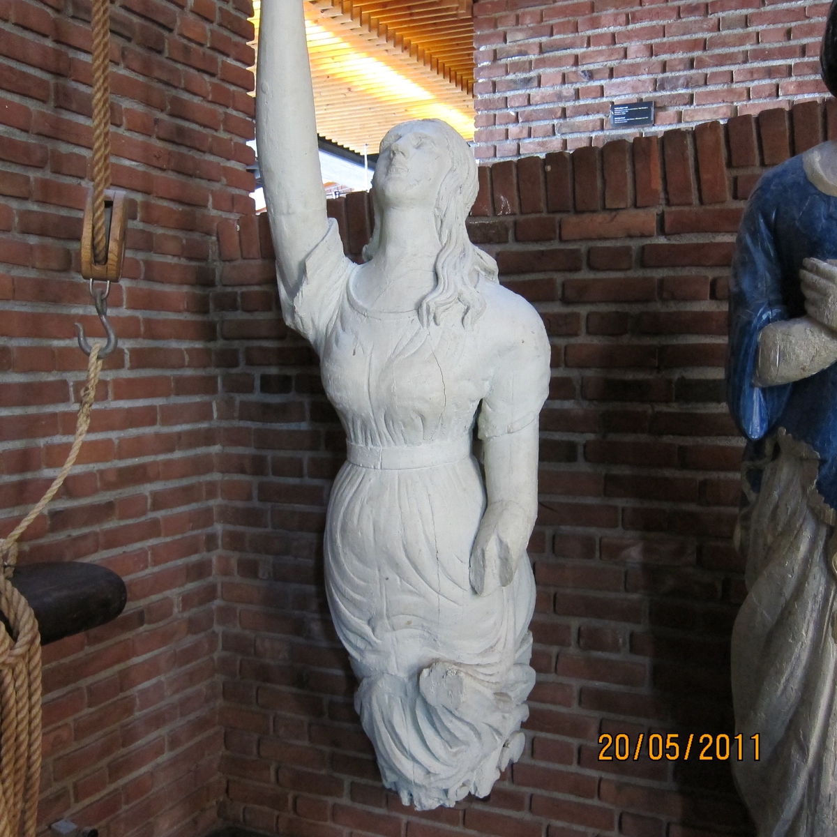 Kvinnefigur med høyre arm hevet, venstre underarm mangler.