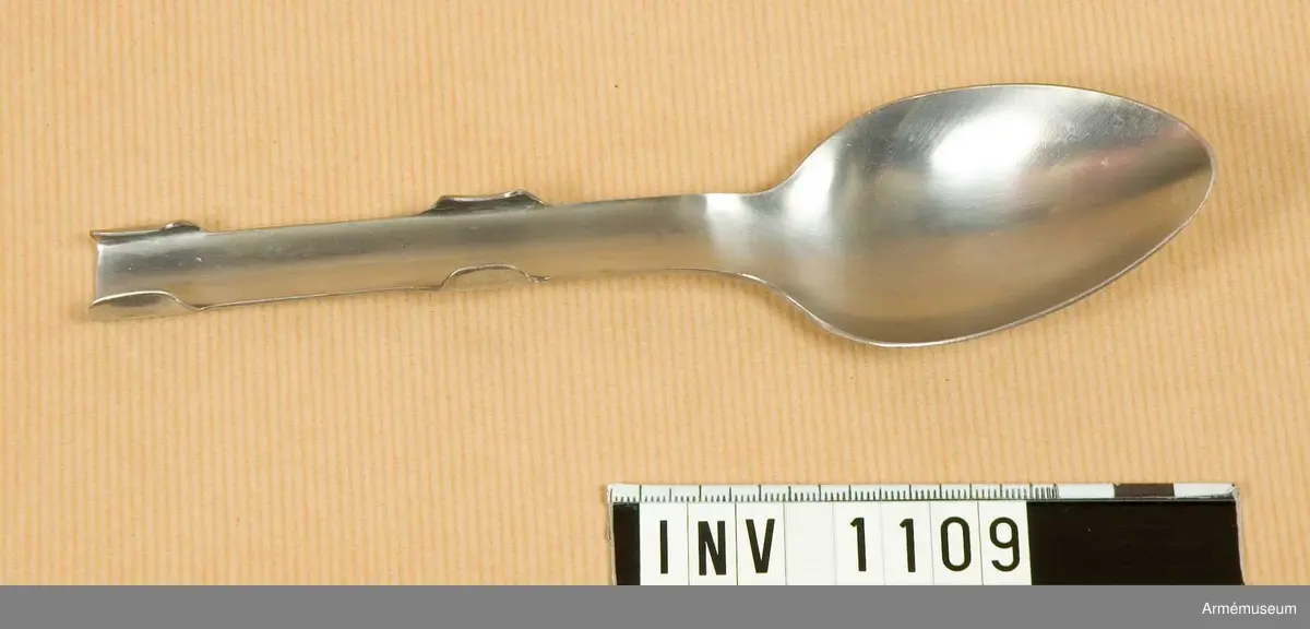 Samhörande nr är 1074-1129, (1109-1111).
Sked m/1929.
Utförd i ett stycke. Skaftet är försett med fyra falsar vilka håller sked, gaffel, och kniv förenade under förvaring och transport. Något speciellt märke för GENSE finns ej på skeden, endast kniven. Har tillhört mob.utrustning vid Armémuseum.