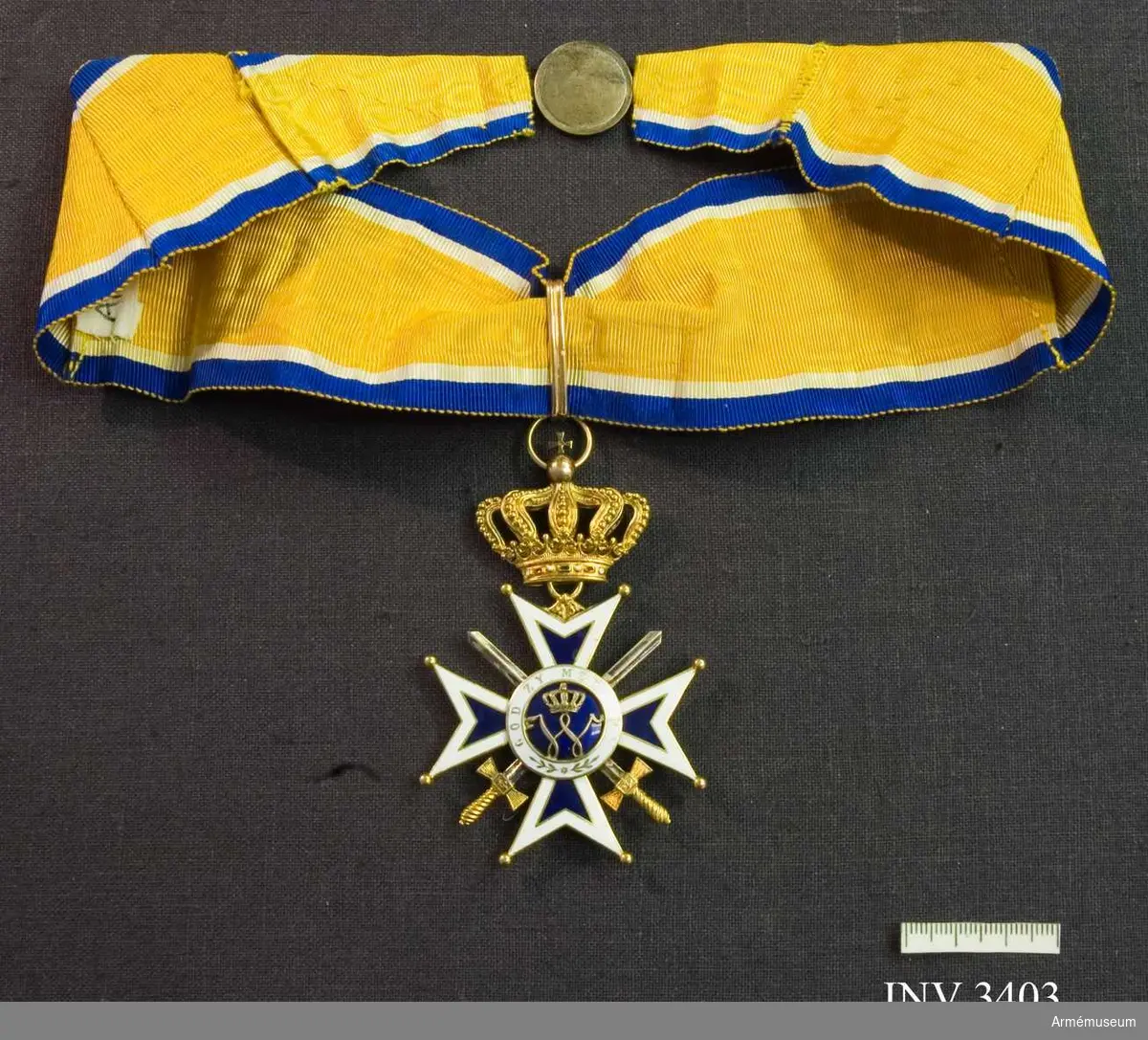 Kommendörstecknet av Nederländska Oranien-Nassau orden m svärd.

I guld och vit och blå emalj. Ordenskorset är ett Georgskors med guldpärlor på spetsarna, ytterkanter av vit emalj och det inre i blå emalj. Två korslagda svärd vilar mellan från och  åtsidan, dessa är i guld. I mitten en blåemaljerad rundel med ett W, krönt med kunglig krona, i mitten, utfört i guld.  Detta är Wilhelminas monogram. (1880-1962). Abdikerade 1948. Runt rundelen ett vitt smaljerat band med i guldskrift: GOD ZY MET ONS (Gud är med oss). 
Frånsidan är utformad på samma  sätt, men i mitten på blåemaljerad botten syns i guld ett  svärdsvingande lejon. På det vita fältet runt lejonet står det: JE  MAINTIENEDRAI (jag vill hålla ut).

Orden hänger i en kunglig krona utförd i guld med runt brämet ädla stenar. Orden hänger i ett gult band  av vattrat siden, med vit och blå kant. Bandet skall knäppas runt halsen.