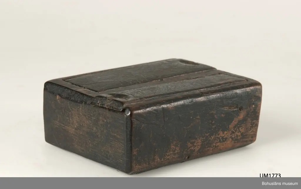 Rektangulär låda med två skjutlock, vilka dras ut åt varsitt håll.
I det större facket förvarades en flintbit eller ett eldstål och i det mindre fnösket att fånga gnistan med.
Den svartmålade färgen har flagnat runtom.
Något skadedjursangrepp.

Litt.; Gjaerder, Per, Esker og tiner, C. Huitfeldts förlag, Oslo, 1981, s. 48-50.

Ur handskrivna katalogen 1957-1958:
Ask, dubbelt skjutlock
Bottenmått. 12,5 x 8 H: 4
Trä, brunmålat. Föremålet helt. Forshälla, Bohusl.

Lappkatalog: 84
