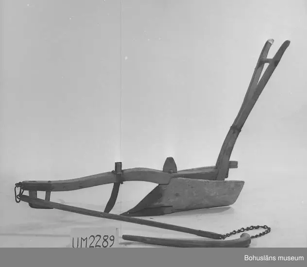 Träårder med smidd plogbill som kopplas till ett dragok. 
Dragårdret sammanhör med Drakok, UM027773

Ur handskrivna katalogen 1957-1958:
Årder att dragas för hand
L. c:a 152 cm. Järnbeslag. Dragträ l. m. kätting. Föremål. Järnet ngt rostigt. Träet maskätet.