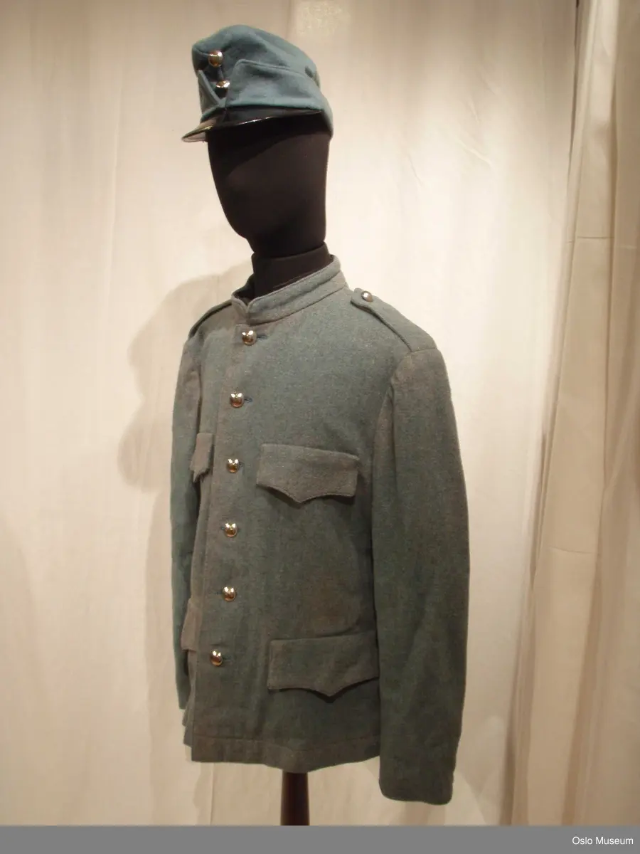 Uniformslue og jakke i blått ullstoff med messingknapper.