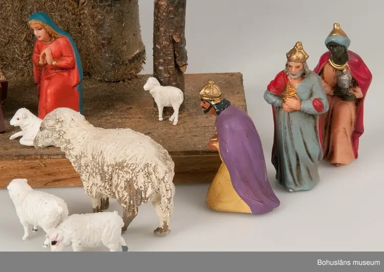 Stall med halmtak, trästolpar samt golv och vägg av masonite. Märkt UM19818:1
18 st figurer tillhör julkrubban. De är märkta UM19818:2.
Krubba, Jesusbarnet, Maria, Josef, en herde, de tre vise männen, en åsna, en oxe, tre liggande får, fem stående får varav ett betydligt större.
En av de tre vise männen märkt: Germany
Elastolin brukar denna typ av plastisk massa benämnas - egentligen ett  tyskt inregistrerat varumärke på en kompositmassa.