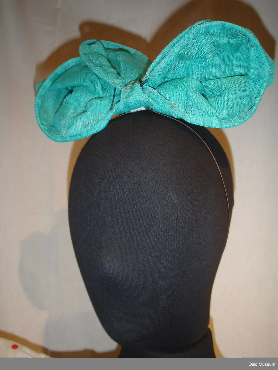 2 bluser i hvitt silkestoff med ermer av transparent, hvitt stoff med røde prikker. Røde kantebånd. Skjørtdel av hvitt tyllstoff med røde prikker og røde kantebånd nederst 2 stk.. 1 stor sløyfe med strikk i grønn tyll.