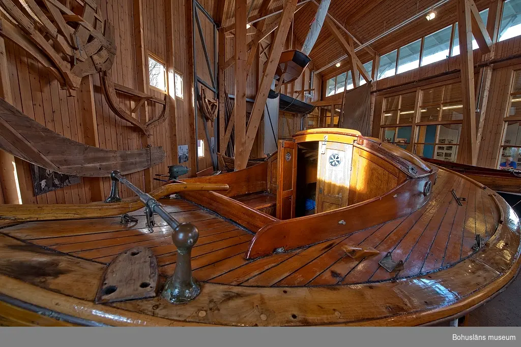 Spetsgattad. Klinkbyggd. Bord och spant av ek. Borden är nitade.
Däck av oregonpine. Ruff av mahogny och oregonepine (taket). Masten (H 10,3 m) och bommen (L 3,1 m) är gjorda av oregonpine.
Tidigare var båten gaffelriggad men i samband med en ombyggnad 1952 fick hon däck, ruff och en ny modern rigg samt kryssfock och storsegel av bomull tillverkat av Hasses segelmakeri i Göteborg, se UM026494 - UM026495. Se Länkade filer under Tilläggsinformation.
På sittbrunnens sarg sitter en namnskylt i trä; "NYMF".
Ett blått kapell, sprayhood, med två vita stänger från 1980-tal samt en båtshake förvaras i ruffen. Se Länkade filer under Tilläggsinformation.

Båten ägdes på 1930-talet av Karl Otto Jonasson. År 1941 sålde han den till Folke Gunnarsson och Rune Olsson. Fem år senare köpte Folke ut Rune.
Folke var med i Segelsällskapet FRAM i Göteborg. Båten kallades Nymf och hade nr 64 i segelsällskapet FRAM. År 1988 tog Karl-Erik Karlsson över båten.

Enligt Sveriges befolkning 1900 heter båtbyggaren Karl Alfred Fredriksson Stjërn, född i Kville 1857.
 
Litteratur: 
Börjesson, E, Börjesson, L., Dunér, m fl.: Kostern. Segelsällskapet Fram 100 år. 1896-1996. Göteborg 1996.
Sörenson, Reiners: Stjerns båtbyggeri på Galtö. Ur Träbiten nr. 93, Föreningen Allmogebåtar, Göteborg 1996.
Hasslöf, Olof: Svenska Västkustfiskarna, Stockholm 1949, sidan 296 ff,
Fredriksen, Christine: EBBA och NYMF - nöjesbåtar vid Bohuskusten. BOHUSLÄN. Årsbok 1999. Handel och hantverk. Bohusläns Hembygdsförbund och Bohusläns museum, s. 87-104.

Se Bilagepärmen UM26491: Träbiten nr 93 samt information från Segelsällskapet FRAM.
Gaffel och äldre bomullssegel finns el. uppgift från givaren kvar.
Uppgifterna kompletterade 2002-09-06/A-LS

Se Bildarkivet UMFA55001:1, familjebild från 1934 samt UM031358, prispokal från 1935.