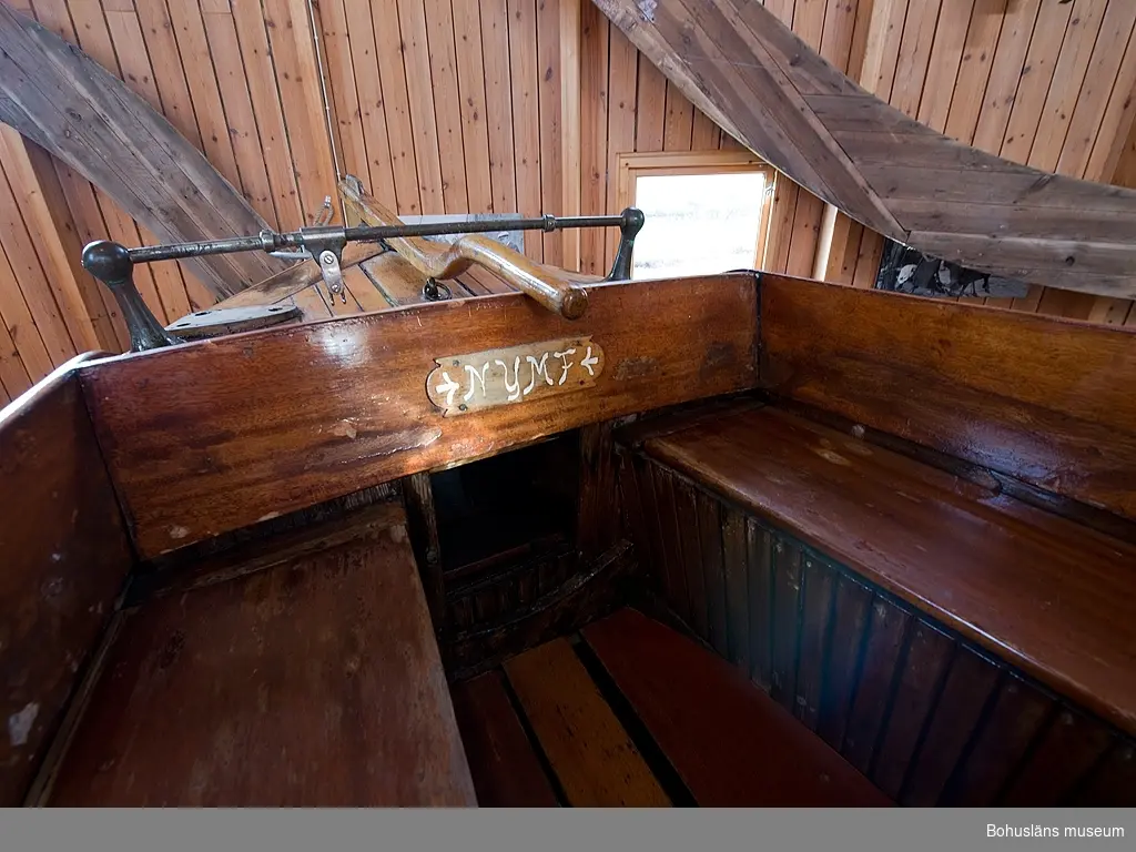 Spetsgattad. Klinkbyggd. Bord och spant av ek. Borden är nitade.
Däck av oregonpine. Ruff av mahogny och oregonepine (taket). Masten (H 10,3 m) och bommen (L 3,1 m) är gjorda av oregonpine.
Tidigare var båten gaffelriggad men i samband med en ombyggnad 1952 fick hon däck, ruff och en ny modern rigg samt kryssfock och storsegel av bomull tillverkat av Hasses segelmakeri i Göteborg, se UM026494 - UM026495. Se Länkade filer under Tilläggsinformation.
På sittbrunnens sarg sitter en namnskylt i trä; "NYMF".
Ett blått kapell, sprayhood, med två vita stänger från 1980-tal samt en båtshake förvaras i ruffen. Se Länkade filer under Tilläggsinformation.

Båten ägdes på 1930-talet av Karl Otto Jonasson. År 1941 sålde han den till Folke Gunnarsson och Rune Olsson. Fem år senare köpte Folke ut Rune.
Folke var med i Segelsällskapet FRAM i Göteborg. Båten kallades Nymf och hade nr 64 i segelsällskapet FRAM. År 1988 tog Karl-Erik Karlsson över båten.

Enligt Sveriges befolkning 1900 heter båtbyggaren Karl Alfred Fredriksson Stjërn, född i Kville 1857.
 
Litteratur: 
Börjesson, E, Börjesson, L., Dunér, m fl.: Kostern. Segelsällskapet Fram 100 år. 1896-1996. Göteborg 1996.
Sörenson, Reiners: Stjerns båtbyggeri på Galtö. Ur Träbiten nr. 93, Föreningen Allmogebåtar, Göteborg 1996.
Hasslöf, Olof: Svenska Västkustfiskarna, Stockholm 1949, sidan 296 ff,
Fredriksen, Christine: EBBA och NYMF - nöjesbåtar vid Bohuskusten. BOHUSLÄN. Årsbok 1999. Handel och hantverk. Bohusläns Hembygdsförbund och Bohusläns museum, s. 87-104.

Se Bilagepärmen UM26491: Träbiten nr 93 samt information från Segelsällskapet FRAM.
Gaffel och äldre bomullssegel finns el. uppgift från givaren kvar.
Uppgifterna kompletterade 2002-09-06/A-LS

Se Bildarkivet UMFA55001:1, familjebild från 1934 samt UM031358, prispokal från 1935.