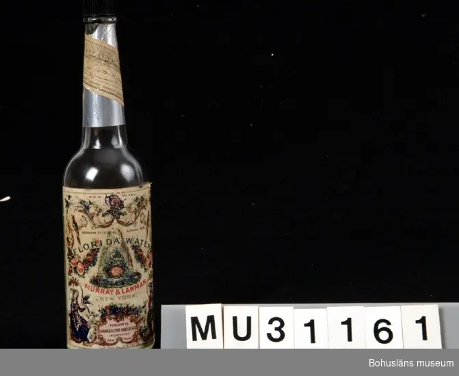 Smal gjuten klar glasflaska med dekorativ pappersetikett och svart bakelitkork. Silverfolie lindad runt flaskans hals med etikett ovanpå.
På flaskan ingjuen text i relief:
FLORIDA WATER
MURRAY &  LANMAN
DRUGGISTS
NEW-YORK
En svag parfymdoft är kvar i flskan.