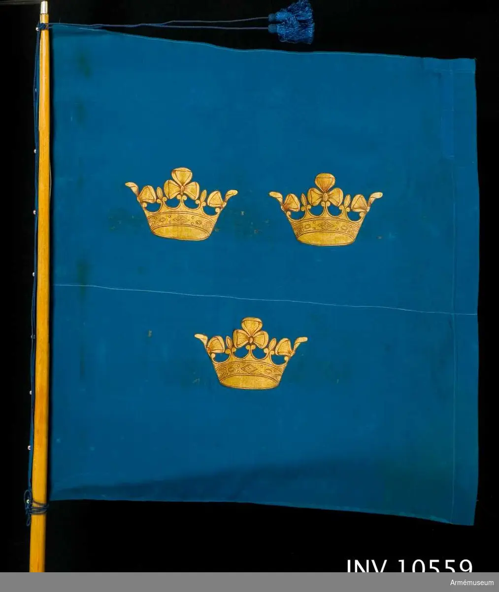 Grupp B I. 
Kommandoflagga f chefen för armén. 1920 eller 1929.
Duk av blå crepe de chine med tre målade guldkronor, placerade två och en. Sydd med en iskarvning längs hela yttersidans höjd. Fastsatt vid den bruna stången med en blå silkesnodd, trädd genom hålförsedda knoppar, 9 st. Spetsen är formad som en bajonett. Till den finns lädertuta.