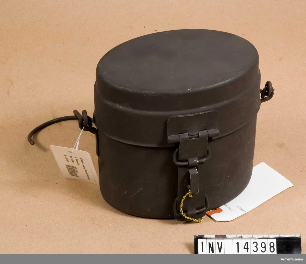 Ovalt kärl av rostfritt stål, mörkgrönt. Stämplat med tre kronor och "5116 gr". Kärlet är försett med gehäng av järntråd.