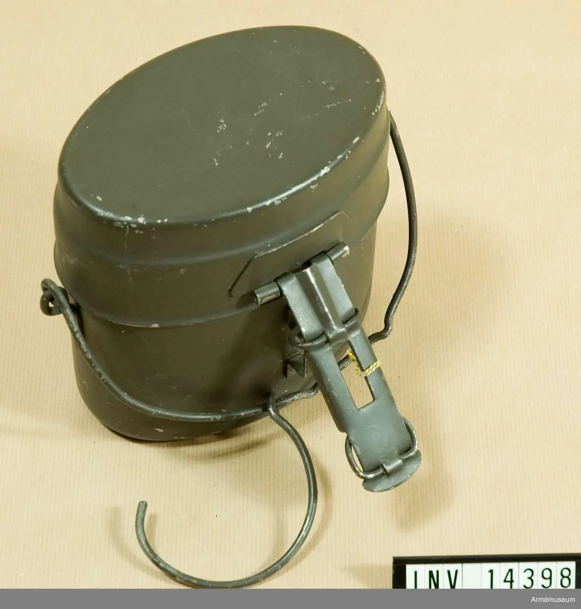 Ovalt kärl av rostfritt stål, mörkgrönt. Stämplat med tre kronor och "5116 gr". Kärlet är försett med gehäng av järntråd.