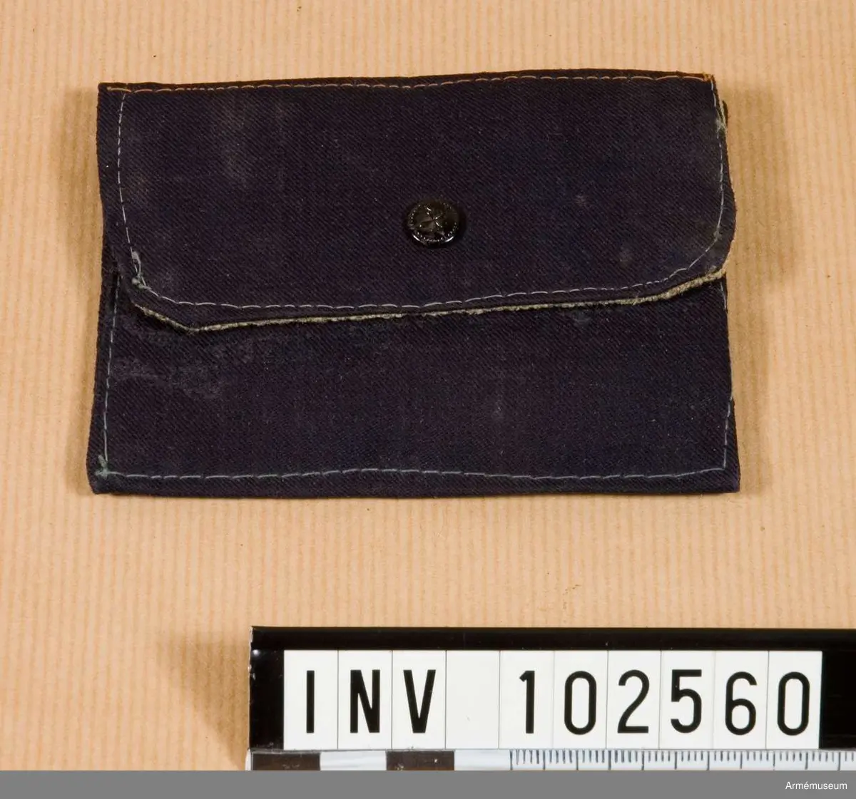Grupp C.
Fodral av blått tyg, fyrkantig, med lock. Foder av grov lärft. Ett svart bomullsband att hänga runt halsen.
Inuti väskan finns ett visitkort på vilket det står: "Carl Ulrich". "Sådan liten väska fick hvar tysk krigare att bära om halsen under kampanjen, den innehöll en dödsbricka för identifiering vid ev. dödsfall". Kriget 1914-1918.
Brickan saknas. Enl W Granberg.