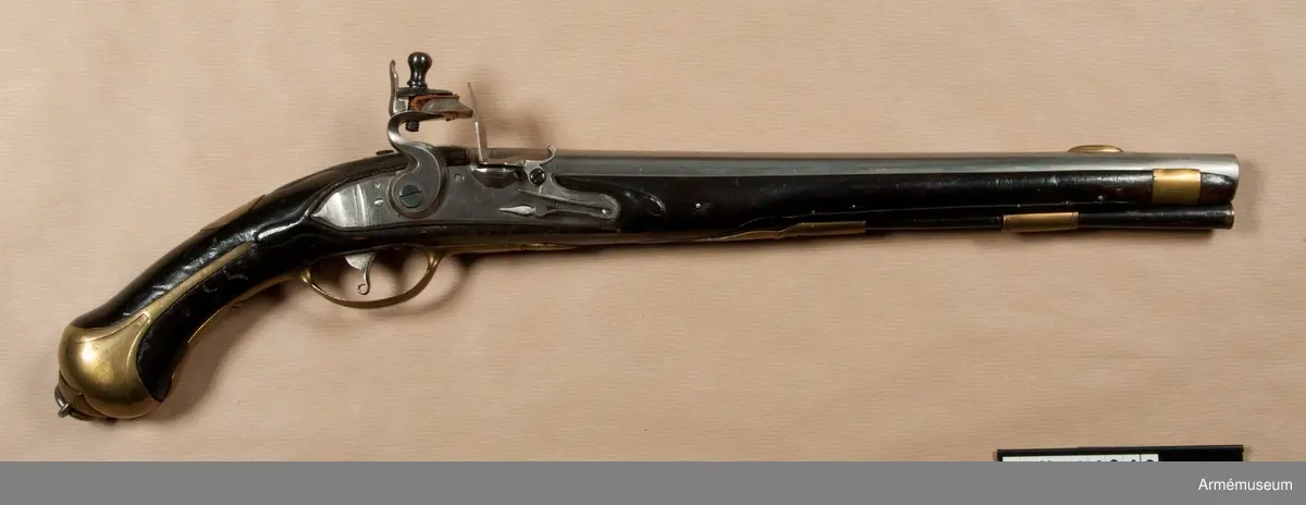 Pistol med flintlås.
Beslag av mässing. Laddstock av trä med mässingsbeslag. På kammarstycket ett krönt F samt bokstaven Ö. På kolvhalsen en mässingsmedaljong med Gustaf III:s krönta namnschiffer. På kolvhalsens H sida nummer 25 inskuret och på dess motsvarande bokstäverna V B. Vid kolvknappen en ring av järn fästad, pistolen tycks vara par med AM 1932:4769.