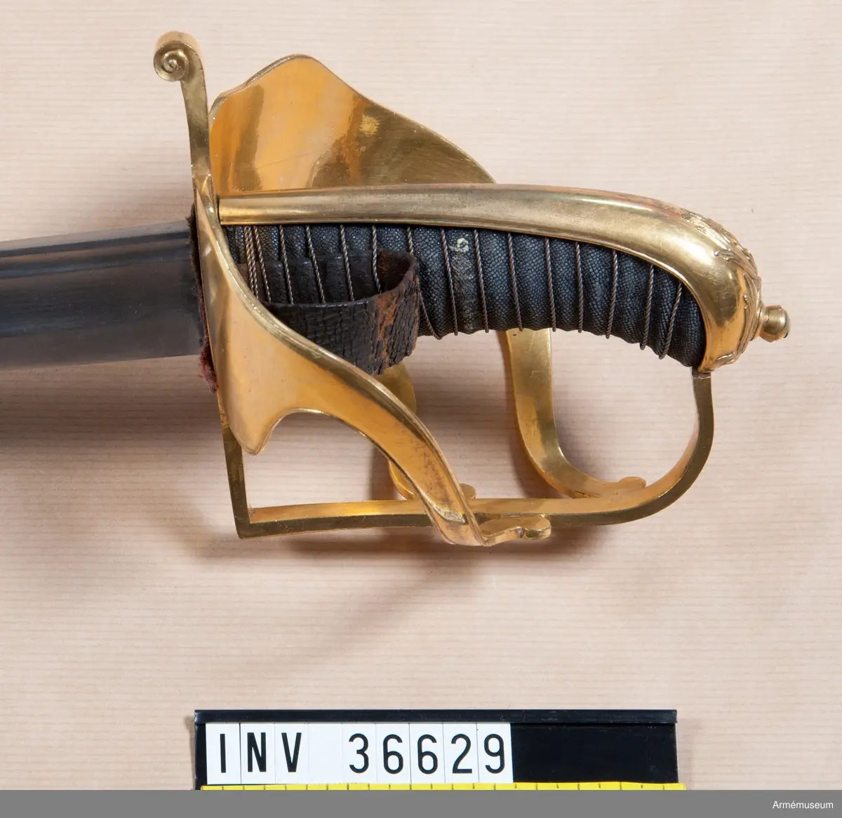 Klingbredd upptill 33 mm. Klingan är krökt och eneggad. Längs ryggen har den en blodrand och framför den en grund skålslipning. Blodranden slutar ungefär 28 cm ovanför udden till blodrandens slut är klingan slipad med egg även å ryggsidan. Fästet är av förgylld mässing. Kaveln är klädd med svärtat fiskskinn, och kring den går en spiralräffla 15 varv. Kaveln har baktill ryggbeslag, som upptill övergår i en låg kappa, vilken pryds med kraftigt ciselerat ornament i form av en stiliserad lagerkrans, vilken omger den lilla fasonerade nitknappen. Parerstången är rak samt har fyrsidigt tvärsnitt. Baktill avslutas den av en nedböjd knapp, vars kanter är ornerade med ciselerade spiraler. På parerstångens övre sida är siffran 3 inslagen. Från parerstångens främre ände utgår handbygeln i rät vinkel. Handbygeln har fyrsidigt tvärsnitt blir bredast framför kappans främre kant. På yttersidan finns en stor uppböjd parerplåt, på vilken finns en krönt oval sköld med tre kronor. Skölden omgives av stiliserade palm- eller lagerkvistar, allt i sicilerat arbete. Från parerplåtens övre spets går en spång, som är böjd i S-form. till handbygeln, som den träffar vid dess övre krök. På andra sidan om föreningspunkten förlängs spången av en liten avrundad utåtböjd flik. En annan liknande spång går fråm parerplåtens främre kant till handbygelns mitt. På innersidan finns en liknande men mindre parerplåt, från vars spets en S-formig spång går till handbygeln, vilken den träffar mitt emellan de ställen, där de båda ytterspängerna förenas med denna bygel. Ryggbeslaget, kappan, handbygelns främre sida, parerplåtarna och alla spänger har längs kanterna en ingraverad rand. På innersidan finns en tumrem, vars ena ände fasthålls av 6 varv av den kring kaveln gående silvertråden och vars ände är instucken mellan kaveln och parerplåten samt är försedd med ett hål, genom vilket tången går.