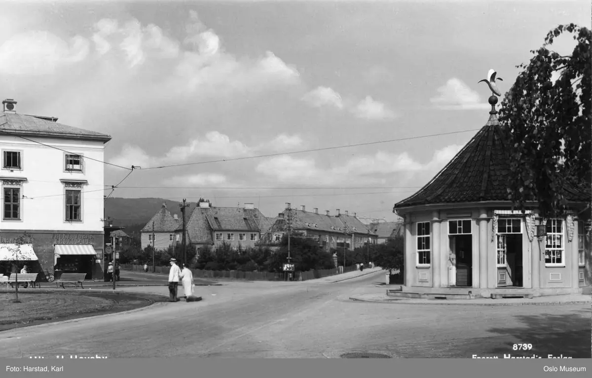 plass, kiosk, venterom, bananreklame på taket, trikkeholdeplass, forretningsgård, rekkehus