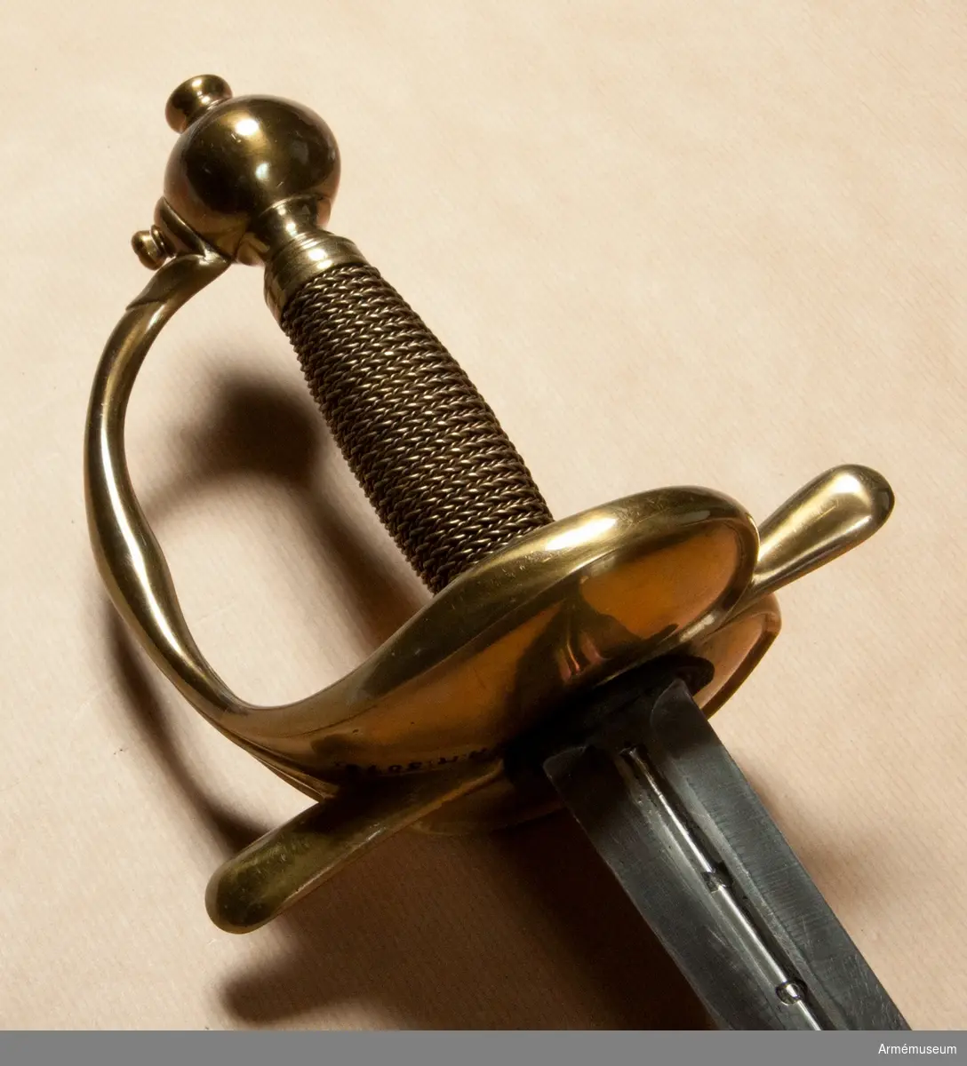 Klingan är tveeggad med flata åsar. På bägge sidor finns upptill en omkring 193 mm lång blodrand. Nedanför blodrandens slut finns på klingan en pilspetsliknande stämpel. 

Fästet är av mässing och av drabanttyp. Knappen har närmast formen av ett vid polerna tillplattat klot, dock med skarp rygg på fram och baksidan. Diametern i sidled är 37 mm, men över ryggarna 40 mm. Höjden är 31 mm. Nitknappens diameter är 16,5 mm, dess höjd 10 mm. Den är instrypt på mitten och har en spetsoval, 20 mm lång fot. Halsen är instrypt på mitten och upptill spetsoval samt 13,5 mm lång. En rand eller snarare avsats markerar gränsen mellan knappen och nitknappen samt mellan knappen och halsen, en dylik går även runt halsens nedre del.
Kaveln har fram och bak en flat kant, men sidorna är avrundade. Den har upp och nedtill ett 9 mm brett beslag av tunt mässingsbleck, vilket är prytt med två ränder. I övrigt är kaveln lindad med två mässingstrådar, en smalare och en tjockare, båda hopsnodda av två parter, den ena höger-, den andra vänstersnodd. Lindningen har Iossnat.
Parerstången är rak och har spetsovalt tvärsnitt. Ändarna är avrundade och parerstången vidgas mot dessa. Avståndet mellan främre eggen och parerstångens framända är 68 mm, men från den bakre eggen till stångens bakända 55 mm. Den största tjockleken är för den främre armen 10 mm, men för den bakre 8,5 mm. Den största bredden är för bägge armarna 16 mm. Avståndet mellan klingans mitt och parerplåtens ytterkant är 45 mm, men mellan klingans mitt och innerkanten 40 mm.