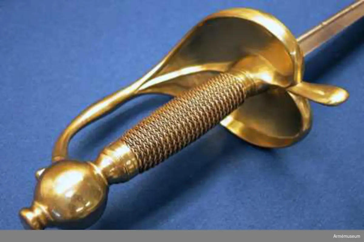 Klingan är tveeggad med flata åsar. På bägge sidor finns upptill en omkring 193 mm lång blodrand. Nedanför blodrandens slut finns på klingan en pilspetsliknande stämpel. 

Fästet är av mässing och av drabanttyp. Knappen har närmast formen av ett vid polerna tillplattat klot, dock med skarp rygg på fram och baksidan. Diametern i sidled är 37 mm, men över ryggarna 40 mm. Höjden är 31 mm. Nitknappens diameter är 16,5 mm, dess höjd 10 mm. Den är instrypt på mitten och har en spetsoval, 20 mm lång fot. Halsen är instrypt på mitten och upptill spetsoval samt 13,5 mm lång. En rand eller snarare avsats markerar gränsen mellan knappen och nitknappen samt mellan knappen och halsen, en dylik går även runt halsens nedre del.
Kaveln har fram och bak en flat kant, men sidorna är avrundade. Den har upp och nedtill ett 9 mm brett beslag av tunt mässingsbleck, vilket är prytt med två ränder. I övrigt är kaveln lindad med två mässingstrådar, en smalare och en tjockare, båda hopsnodda av två parter, den ena höger-, den andra vänstersnodd. Lindningen har Iossnat.
Parerstången är rak och har spetsovalt tvärsnitt. Ändarna är avrundade och parerstången vidgas mot dessa. Avståndet mellan främre eggen och parerstångens framända är 68 mm, men från den bakre eggen till stångens bakända 55 mm. Den största tjockleken är för den främre armen 10 mm, men för den bakre 8,5 mm. Den största bredden är för bägge armarna 16 mm. Avståndet mellan klingans mitt och parerplåtens ytterkant är 45 mm, men mellan klingans mitt och innerkanten 40 mm.