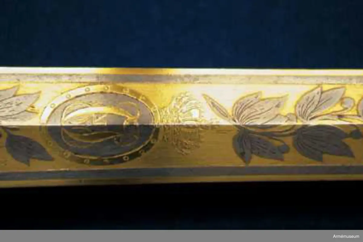 Grupp D II.
Klingan är tveeggad med ryggar. På vardera sidan är den på en längd av omkring 32 cm prydd med blanka, etsade ornament på förgylld botten, däribland på yttersidan Karl XIV Johans namnchiffer och en ranka med lagerlöv, på insidan med tre kronor under kunglig krona samt en ranka med eklöv och ollon. Fästet är av förgylld mässing och av karolinsk kavallerityp. Knappen har formen av ett tillplattat klot samt har fram och bak en rygg markerad av en längs kanterna upphöjd rand. Nitknappen är rätt hög, svagt fasonerad och med ganska stor fot. Nedtill  fortsätts knappen av en på mitten instrypt hals. Runt halsens nedre del går en rand. Gränsen mellan hals och knapp samt mellan knapp och nitknapp är tydligt markerad. Kaveln omges upp- och nedtill av ett ringliknande, omkring 5 mm brett beslag av förgyllt mässingsbleck. Längs varje kant pryds dessa beslag av en ingraverad rand. I övrigt är kaveln lindad  med en tunn, av två parter hopsnodd försilvrad koppartråd. Parerstången vidgas rätt kraftigt mot de i trepass avslutade ändarna samt har ovalt tvärsnitt. Längs dessa övre och undre, främre och bakre kanter går en upphöjd rand. Parerplåten är hjärtformig. Dess förhöjda kanter är på mitten vidgade och har på samma ställe en kantig utbuktning på den mot plåten motsatta sidan. Handbygeln vidgas rätt kraftigt på mitten och har ovalt tvärsnitt. Dess övre ände är medelst en skruv fäst vid knappen. Längs över- och undersidan på de förhöjda kanterna samt längs handbygelns främre och bakre kant löper en upphöjd, smal rand. På översidan av parerplåtens yttre hälft är de ciselerade bokstäverna F J O (Frans Josef Oskar) fastnitade och på samma sida av den inre hälften är en kronprinskrona i liknande arbete fäst.