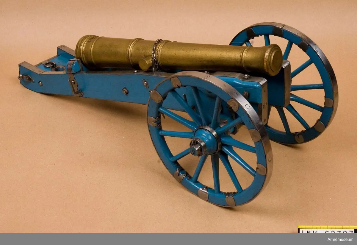 Grupp F I. 
Skala 1/8.
Modell i trä av 18-pundig metallkanon, Cronstedts system 1725.
Kapten F A Spaks katalog år 1888. Samhörande är lavett, föreställare och två svänglar.