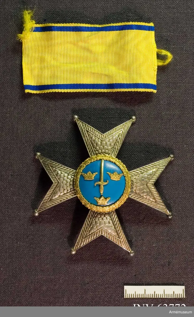 Grupp M II.
Kraschan tidigare buren av översten T.G.R Bergenstråhle. Ett johannitkors av silver med åtta uddar som var och en avslutas med en kula. Ljust mellanblå emaljerad glob med ornerad kant med nött förgyllning. Inom kanten ett stolpvis ställt omgivet av tre öppna kronor, ställda två och en - av guld eller förgyllt. På baksidan kontrollstämplar: "GFC", sk kattfot, "S", svårtydd stämpel samt "G 8".  Tillsammans med kraschanen ligger en bit band, 70 mm x 37 mm, gult med mörkblå kantränder.