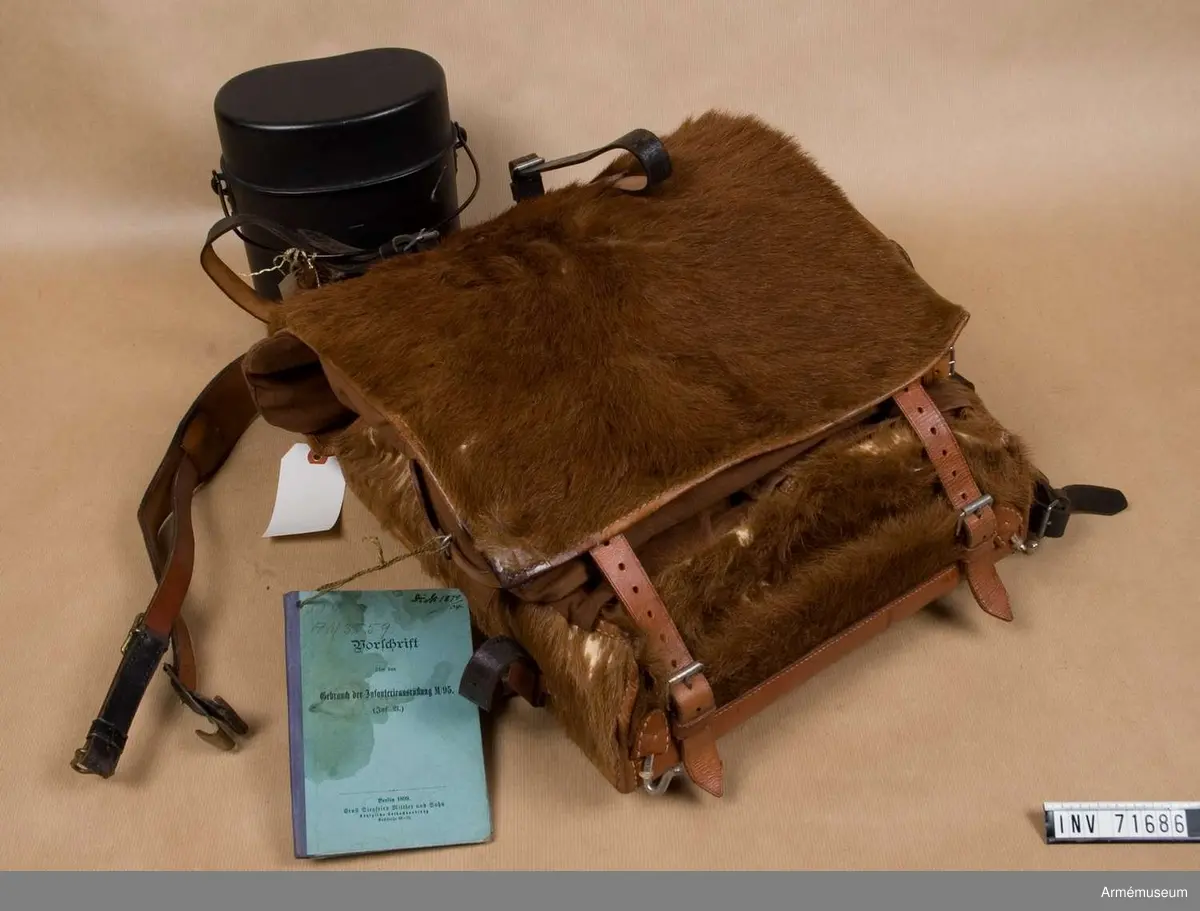 Innerhåller stövlar m/1884, långkalsonger m/1903, instrumentbok, tre delar till tältstång, tältpinnar, två matpåsar tre dosor för fett, en påse i kläde, ett kokkärl och en konserv. 
En del av utrustningen är från år 1904.

I de två hörnen på locket finns små fickor för patroner och tältutredningen förvaras i ett separat fodral som knäpps fast under locket.

Stövlarna är märkta "3.G.R." på flera ställen och "1884". Sulorna är stämplade "29" och "9½". De är sydda med köttsidan utåt och sulorna är pliggade med träpligg samt försedda med klackjärn. På den ena stövelns hälla bak sitter en etikett med text: "Tyska stöflar bekommna år 1884".

Långkalsongerna är 115 cm långa, har en bakficka på högra sidan och en mindre framficka för fickur samt ett tygband för att fästa urets kedja. De är tillverkade i kypertvävd bomulls och har bomullsband vid anklarna och i linningen samt knappar för hängslen och i gylfen. Knapparna är tillverkade i zink. De är på insidan märkta "B.A.G. 1903". Urfickan och bandet i linningen daterar dem till m/1903.

Den vidhängande boken beskriver hur utrustningen ska packas. Boken heter: "Vorschrift über den gebrauch der Infanteriausrüstung m/95 (inf. U.)". Tryckt 1899 i Berlin.

Fodralet till tältdelarna är av m/1896 och tältstångdelarna samt tältpinnarna m/1902. Kokkärlet är av m/1910.

Dateringar och information enl. Ulrich Herr, The German Infantry from 1871 to 1914, vol. 1.