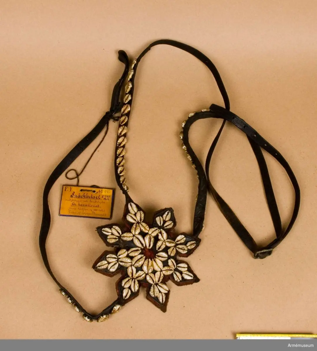 Brode kallas: Snäckbetsel samhörande förbygel och ländstycke. Allt besatt med kauri snäckor.
S n ä c k b e t s l e t utgöres av b r i d o n g och s t å n g b e t s e l.
B r i d o n g e n består av huvudlag, bridongbett och bridongtyglar. 
Huvudlaget består av:
a/ två sidstycken, fastsydda vid tygelringarna och på vänstra sidan hopspända med varandra. 
b/ pannrem, rörlig.
Bridongbettet är mycket smäckert, tredelat, med runda 30 mm stora tygelringarna.
Bridongtyglarna äro hopsydda med varandra och fastsydda vid tygelringarna.
S t å n g b e t s l e t består av huvudlag, stångbett och stångtyglar.
Huvudlaget består av:
a/ två sidstycken, hopspända med varandra över hästens nacke och sammanfästa med stångbettet och flyglarna.
b/ två flyglar, hopspända med sidstyckena. 
c/ pannrem är fastsydd vid sidstyckena och har två stroppar. 
d/ käkrem är tvådelad och förlängd samt hopspänd med pannremmens stroppar.
e/ kryssrem med fem rosetter.
f/ nosrem löper rund om nosen och käken och är försedd med en sölja. 
Stångbettet har tvådelat mellanstycke, fasta sidstänger, vridbara tygelringar och lös kindkedja.
Stångtyglarna äro försedda med en löpare, hopspända i tygelringarna, hopsydda med varandra och sammanfästade med en flätad ridpiska.
Förbygeln är försedd med en 170 mm stor åttauddig stjärna.
Ländstycket är försett med tre rosetter. 
(Kikulis 1954)
1800-1850.