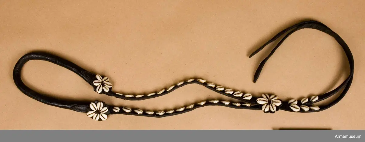 Brode kallas: Snäckbetsel samhörande förbygel och ländstycke. Allt besatt med kauri snäckor.
S n ä c k b e t s l e t utgöres av b r i d o n g och s t å n g b e t s e l.
B r i d o n g e n består av huvudlag, bridongbett och bridongtyglar. 
Huvudlaget består av:
a/ två sidstycken, fastsydda vid tygelringarna och på vänstra sidan hopspända med varandra. 
b/ pannrem, rörlig.
Bridongbettet är mycket smäckert, tredelat, med runda 30 mm stora tygelringarna.
Bridongtyglarna äro hopsydda med varandra och fastsydda vid tygelringarna.
S t å n g b e t s l e t består av huvudlag, stångbett och stångtyglar.
Huvudlaget består av:
a/ två sidstycken, hopspända med varandra över hästens nacke och sammanfästa med stångbettet och flyglarna.
b/ två flyglar, hopspända med sidstyckena. 
c/ pannrem är fastsydd vid sidstyckena och har två stroppar. 
d/ käkrem är tvådelad och förlängd samt hopspänd med pannremmens stroppar.
e/ kryssrem med fem rosetter.
f/ nosrem löper rund om nosen och käken och är försedd med en sölja. 
Stångbettet har tvådelat mellanstycke, fasta sidstänger, vridbara tygelringar och lös kindkedja.
Stångtyglarna äro försedda med en löpare, hopspända i tygelringarna, hopsydda med varandra och sammanfästade med en flätad ridpiska.
Förbygeln är försedd med en 170 mm stor åttauddig stjärna.
Ländstycket är försett med tre rosetter. 
(Kikulis 1954).
1800-1850.