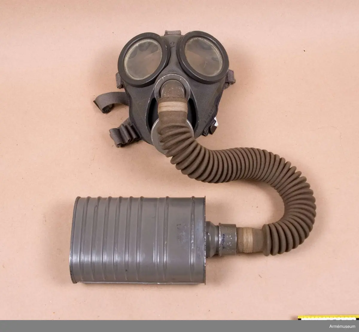 Grupp J.
Gasmask m/1931. Komplett med väska.
Består av ett ansiktsskydd m/1931, en ask för imskivor i reserv, en ask för ventilhus i reserv, en behållare m/1931, en slang, två ventilhus samt en väska m/1931.