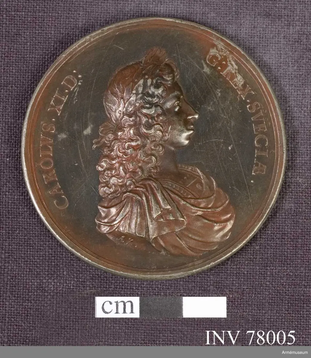 Grupp: M. 
Åtsidan: CAROLVS. XI. D. G. REX. SVECIÆ. Bröstbild åt höger, lagerkransad, i harnesk med fyrkantig öppning om den bara halsen och mantelveck upplagda över axeln - under armen: A. K.

Frånsidan: IN SPEM ET GLORIAM TEMPORVM. Konungen, i antik krigsdräkt, hållande i högra handen en upprätt lans och två lagerkransar, (De två lagerkransarna hava avseende på segrarna vid Halmstad och Lund.) stödjande den venstra på en sköld. I avskärningen: A. K.