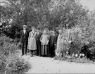 Grupp porträtterad i den grönskande trädgården på Rultane.
Från vänster: Artur, Naemi, Johannes, Anna (alla med efternamnet Pettersson), okänd, Augusta Forsberg och okänd.
Tillsammans med flox och astrar och framför meterhög gullboll lät sig gruppen fotograferas.