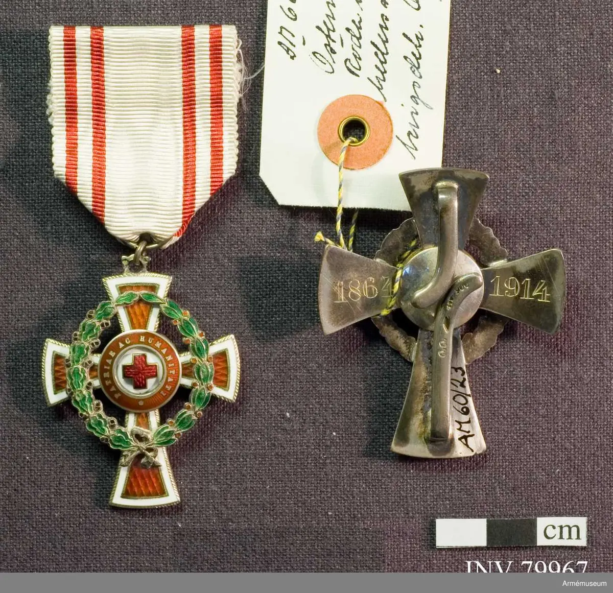 Ett rödemaljerat kors av silver med en vit bård vars nedre korsarm är förlängd. Runt korset en bård av vit emalj och innanför är korset av röd emalj. På korsets mitt en röd emaljerad cirkel med inskriptionen "PATRIAE AC HUMANITATI" (Fäderlandet och mänskligheten). Innanför cirkeln Röda Korsets emblem.

Mitt på korset till vänster sett framifrån en grön emaljerad krans av lager och till höger av eklöv på korsarmarna, vilket visar att utmärkelsen är en krigsdekoration.

På baksidan återfinns de två åren 1864 och 1914 i en cirkel mitt på korset.

Dekorationen är upphängd i ett vitt band med smala röda ränder.