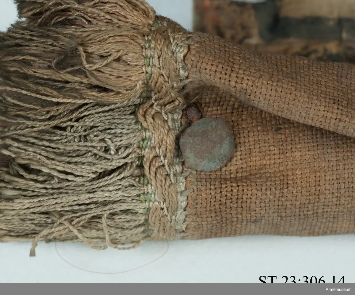 Duk av vit sidentaft och strumpa av rött linne försedd med frans vid öppningarna. Motivet målat i guld- och silver samt rött och grönt bestående av en krönt örn, måne, sol och stjärnor, På duken en pappersetikett som anger att den tagits i slaget vid Saladen 1703.