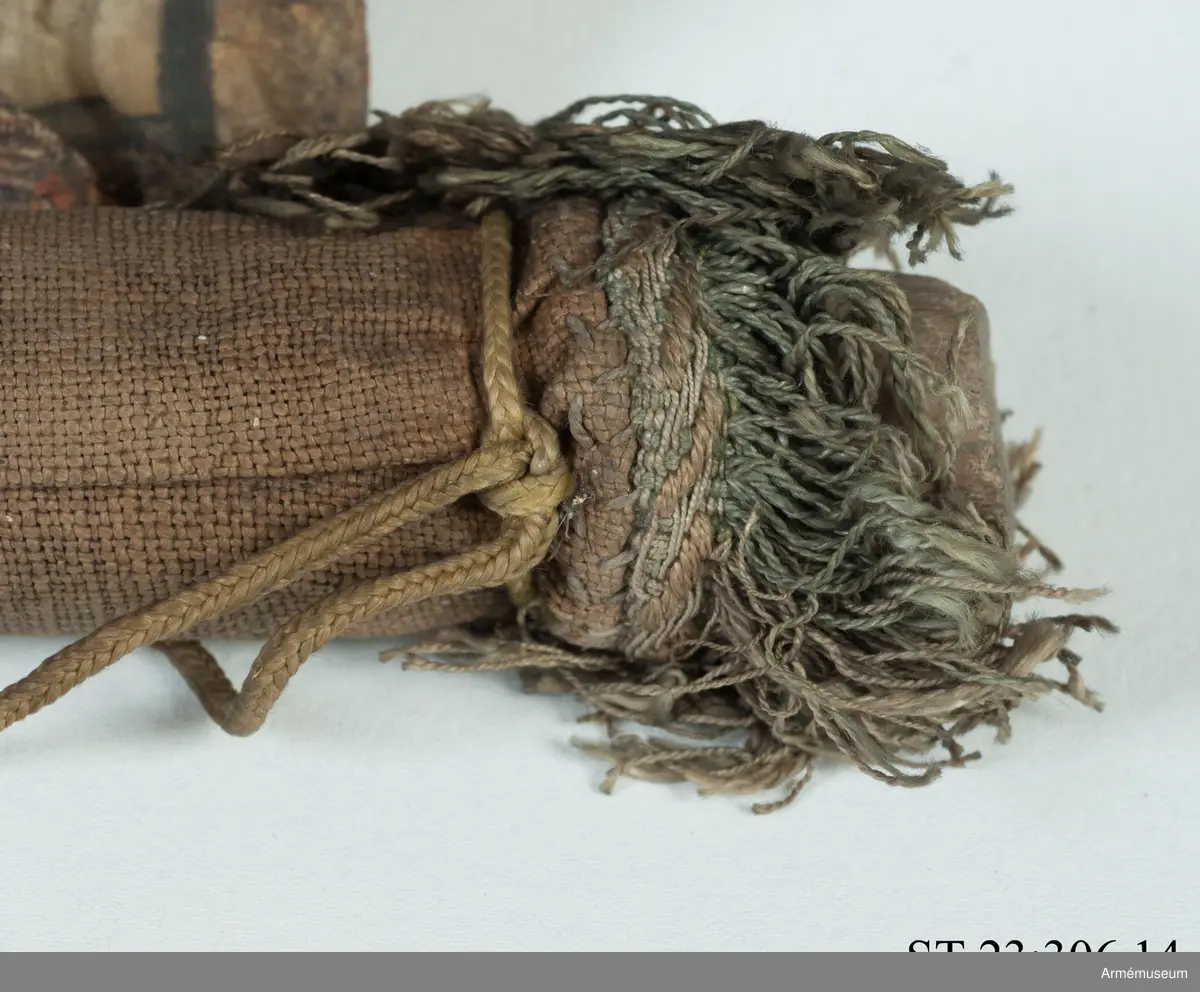 Duk av vit sidentaft och strumpa av rött linne försedd med frans vid öppningarna. Motivet målat i guld- och silver samt rött och grönt bestående av en krönt örn, måne, sol och stjärnor, På duken en pappersetikett som anger att den tagits i slaget vid Saladen 1703.