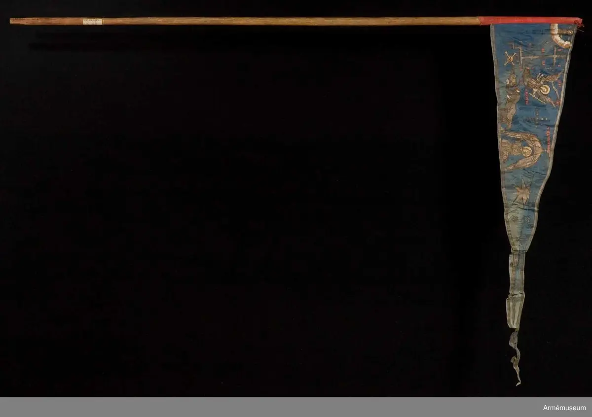 Duk av blå kinesisk sidendamast med målad dekor. Motivet föreställer den romerske kejsaren Konstantins vision av ett kors i skyn kvällen innan slaget vid Pons Mulvius år 312 e Kr mot Maxentius. En ärkeängel med svärd i handen (Gabriel?) svävar över den halshuggne Maxentius. Denna händelse ses som förklaring till att kristna kors började användas på militära fanor. Närmast stångsidan är också ett Golgatakors avbildat. Över detta syns ett moln där Kristus är avbildad. 
Strumpa av rött linne.