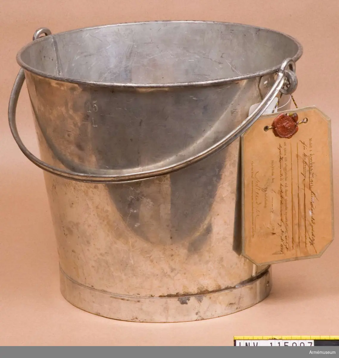 Text på vidhängande modelllapp:
"Modell å ämbar m/1901 tillhörande verktyg för bakning att tjäna till efterrättelse vid deraf skeende nyanskaffning enligt departementets beslut denna dag Dii No 1505. Stockholm den 1 mars 1901"