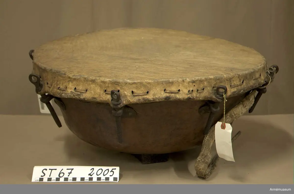 Kittel av koppar och skinn av kalv med fast spännring. Fot av järn fastnitad med kopparnit. Skruvar och skruvfästen av järn. Bärrem av kalvskinn i två lager med spänne av järn.