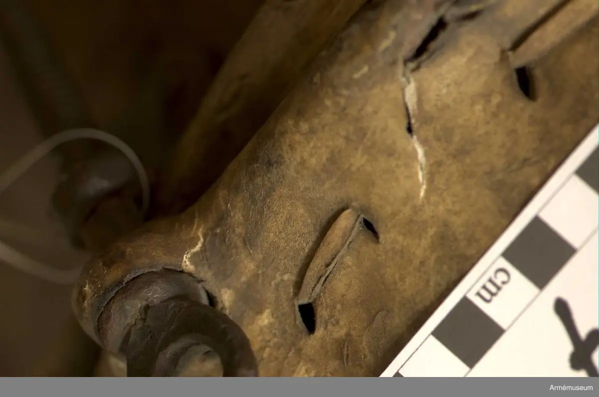 Kittel av koppar och skinn av kalv med fast spännring. Fot av järn fastnitad med kopparnit. Skruvar och skruvfästen av järn. Bärrem av kalvskinn i två lager med spänne av järn.