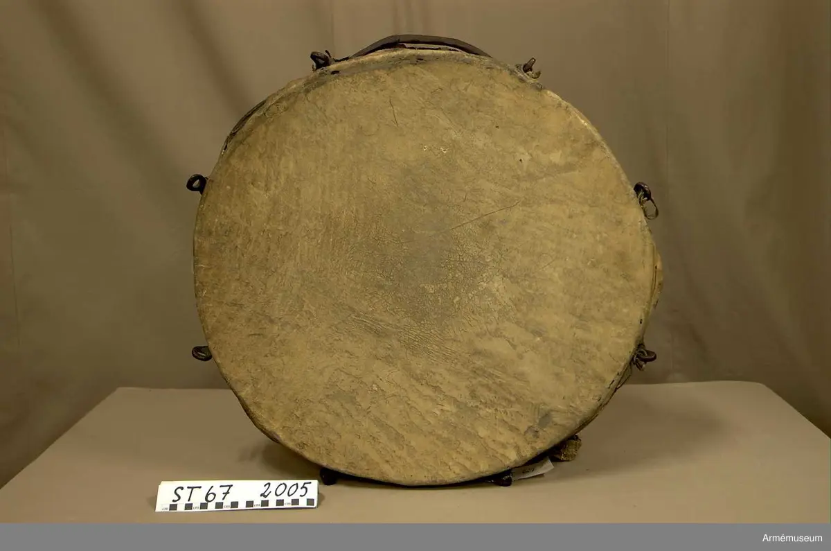 Kittel av koppar och skinn av kalv med fast spännring. Fot av järn fastnitad med kopparnit. Skruvar och skruvfästen av järn. Bärrem av kalvskinn i två lager med spänne av järn.