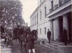 Kronprins Gustaf (V) med stab till häst utanför byggnad.