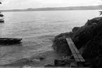 Vy över sjön, en roddbåt ligger i vattnet och en träspång ligger på den bergiga strandkanten.