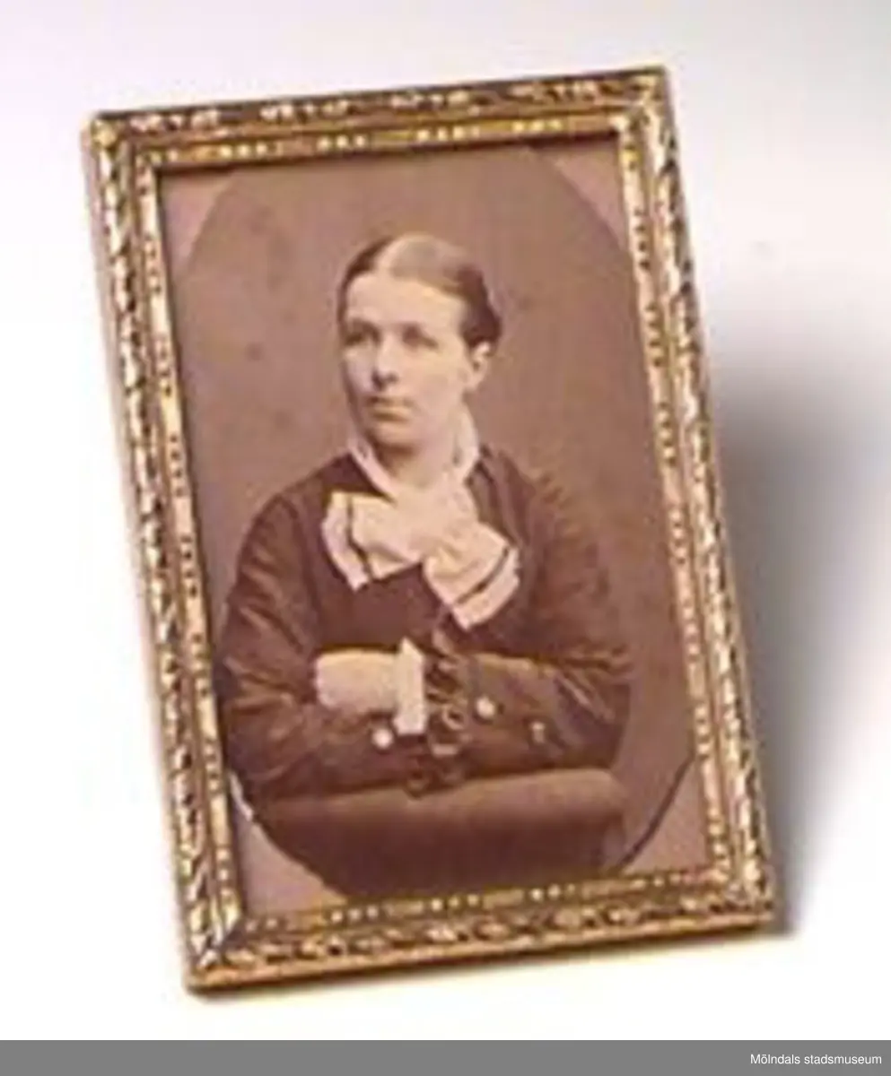 Ett porträttfoto med ram i mässing. Det ovan angivna måttet beskriver fotots mått. Mässingramen har måtten; H: 93 mm. B: 64 mm. Tj: 7 mm.Avporträtterad person är Josefina K Eriksson i  Våmmedal.Tidigare sakord: porträttfoto med ram.