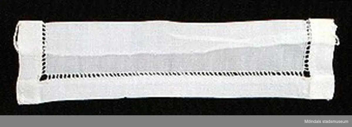 12 par vita lösmanschetter använda tillsammans med långärmade plagg. En del märkta med nr 41. 02253_1 L: 160 mm B: 55 mm._2 L: 160 mm B: 45 mm._3 L: 170 mm B: 60mm. Ribbat tyg._4 L: 190 mm B: 55 mm. Ribbat tyg._5 L: 200 mm B: 50 mm. Hålsömsprydda._6 L: 165 mm B: 80 mm. Hålsömsprydda (ej stärkta, märkta 15)._7 L: 160 mm B: 80 mm. Hålsömsprydda._8 L: 200 mm B: 50 mm. Hålsömsprydda._9 L: 180 mm B: 50 mm. Öglemönstrad spets längs kanten._10 L: 170 mm B: 55 mm. Smal spets längs kanten._11 L: 160 mm B: 45 mm. Spets längs kanten._12 L: 165 mm B: 50 mm. Ögleartad spets längs kanten.Paren förvaras i en tom chokladask (Cloetta Bristol praliner). Dessa har använts av vårdarinna Karin Hasselberg på Stretered.