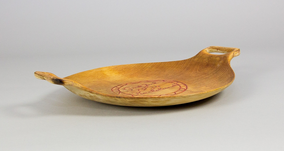 Fat av trä. Runt med två handtag. Svarvat och skuren. Skuren och målad dekor i fatets spegel i form av en julhälsning: "God Jul 1934 Karlslund" i en rund bård med våglinje. Även skuren och målad dekor handtagen.