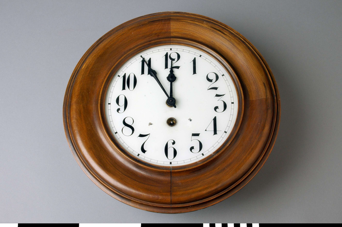 Väggur A, med löstagbar baksida B, och pendel C.
Rund urtavla med arabiska siffror och rund ram. Två visare, ett hål för uppdragning och en åttauddig stjärna med ett J och "UNGHANS" inuti. 
Urverket sitter i en låda av trä skruvad mot urtavlan. Lådan med två runda glasfönster, ett på var sida, och en nedfällbar botten. Det är märkt med samma stjärna som urtavlan och texten: WURTTEMBERG, B 25, 168. Upphängning i lådans översida. 
Anteckningar: Rep 27/765 Frej (? svårläsligt), 2209 Fm, 68 38 R, 77557 gb, gb rep 5/6-62. En stämpel i rött: L 18256.