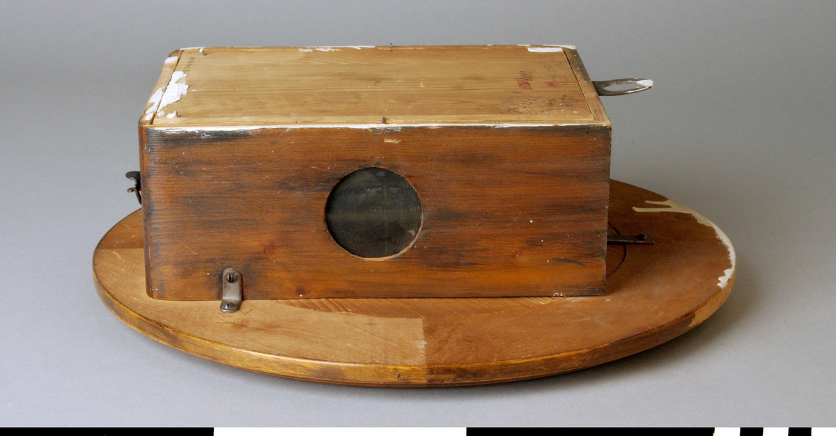 Väggur A, med löstagbar baksida B, och pendel C.
Rund urtavla med arabiska siffror och rund ram. Två visare, ett hål för uppdragning och en åttauddig stjärna med ett J och "UNGHANS" inuti. 
Urverket sitter i en låda av trä skruvad mot urtavlan. Lådan med två runda glasfönster, ett på var sida, och en nedfällbar botten. Det är märkt med samma stjärna som urtavlan och texten: WURTTEMBERG, B 25, 168. Upphängning i lådans översida. 
Anteckningar: Rep 27/765 Frej (? svårläsligt), 2209 Fm, 68 38 R, 77557 gb, gb rep 5/6-62. En stämpel i rött: L 18256.