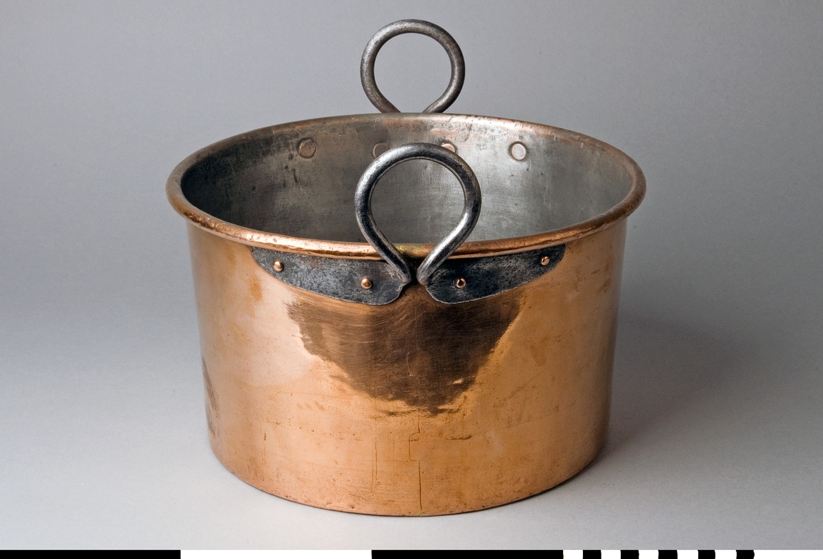 Gryta med lock tillverkad av koppar. Lock med bygelhandtag fäst med två nitar. Fals runt kanten. Märkning på bygeln: C.A.C. Locket är troligen av senare tillverkning. Grytan har en förtent insida. Lätt utåtlutande sidor, 167 mm höga. Överkanten är rullad utåt runt en stödtråd. Runda grepar av grov järntråd med utsmidda avlånga fästen, fyra rullade nitar till varje grep.