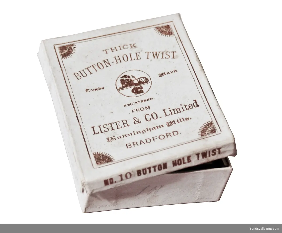 SuM 5195:1-6 sybehör i vit ask, SuM 5195:1,  med texten 'THICK BUTTON-HOLE TWIST Trade Mark REGISTRED FROM LISTER & CO. Limited Manningham Mills, BRADFORD' på locket. På en kortsida sitter en etikett med texten 'BLACK' fastklistrad. SuM 5195:2 nålbrev tillverkat av papper med blått broderat mönster och monogrammet 'ZS', samt invändigt textil, genom vilket nålar är trädda. SuM 5195:3 kors av metall som är upphängt på blått band. SuM 5195:4-5  nålar i papper. SuM 5195:6 säkerhetsnål. Monogrammet 'ZS' kan ev. stå för Selma af Sandeberg.